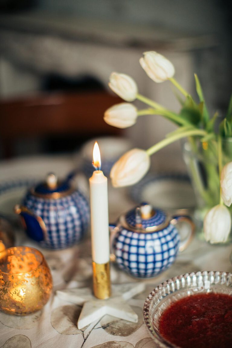 Candle burning near flowers and tableware